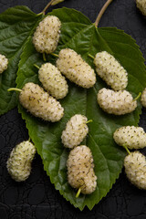 white mulberry on a green leaf on a black background