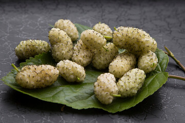 white mulberry on a green leaf on a black background