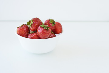 Close Up on fresh ripe red strawberries in a ceramic white bowl on a white background, isolated