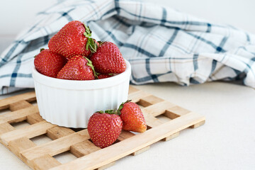 Close Up on Fresh ripe red strawberries in ceramic white bowl on rustic wooden stand, natural food