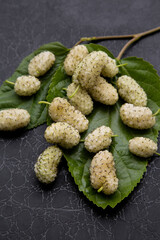 white mulberry on a green leaf on a black background