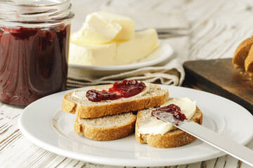 Slice of fresh bread with butter and jam on table