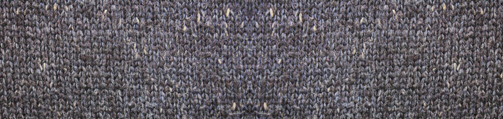 Dark grey woven fabric texture background. Knitted garment cloth pattern with many loops of wool. Woven gray cloth close up, gray color warm winter clothing or scarf design