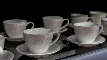 Obraz na płótnie Canvas White tea cups in a row on a dark background