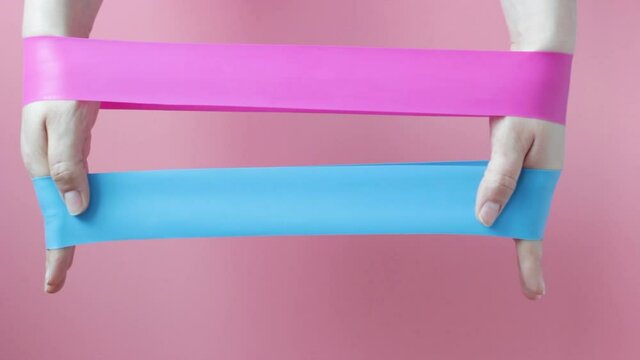 The girl holds two fitness gums, Espander on pink background, view from above