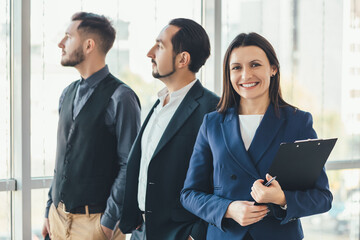 Happy business people standing side by side, smiling, enjoying time in such a team.