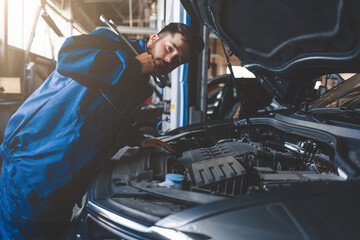 Auto mechanic with wrench over car hood. Car repairman in the service garage
