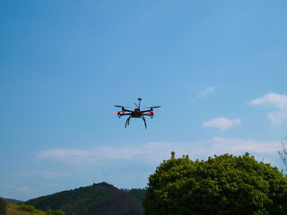 Flying drone in the blue sky. Mountains in the background.