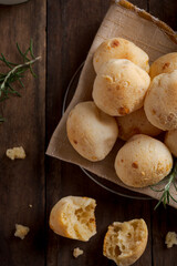Basket of cheese breads with crumbs on wooden table top view close up