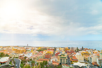 Landscape of the city by the ocean with a blue ske with clouds. Puerto de La Cruz on a sunny day. Tenerife, Spain