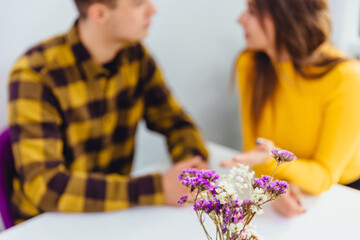 Cropped shot of romantic couple having romantic dinner on special event. Focus on violet flowers on the forefront.