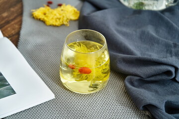 A hot chrysanthemum drink with goji berries and sliced dates in it.
