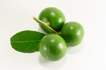 Thai lemons are placed in front of the fruit cluster and separated from a white background.