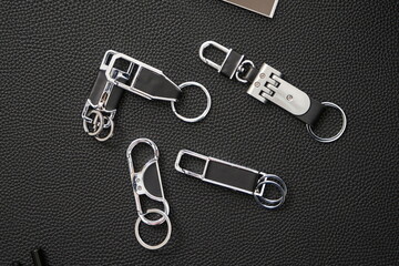 Various styles of delicate keychains cluttering the leather background, top view