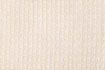 Beige knitted fabric texture background, machine knitting texture. Light bedcover close-up