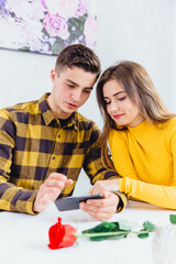 Couple choose some products to buy online, using smartphone. Boy and girl weared in yellow clothes.