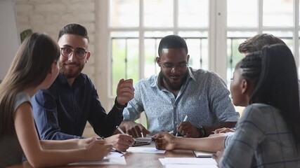Happy friendly diverse startup team people talking laughing doing paperwork noting working together in successful teamwork share creative ideas sit at office meeting table at group corporate briefing - Powered by Adobe