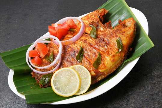 Kerala fish curry, Karimeen Pollichathu a popular hot and spicy baked fish in banana leaves Alleppey India.  pearl spot fish is marinated with Indian spices then wrapped in plantain leaf and grilled. 