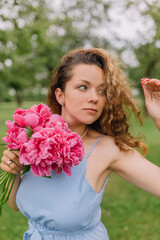 Naklejka premium girl model mother on her head curly curls holding peonies and flowers in her dress gently presses them to herself on the nature in the park