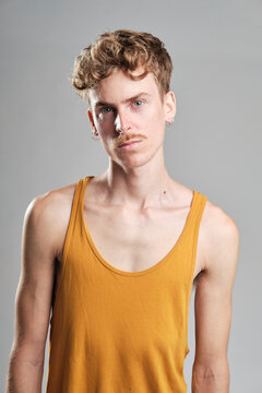 young blond boy with mustache and a yellow t-shirt wearing earrings standing looking at camera