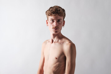 young blond boy bare chested with mustache and wearing earrings  standing looking at camera