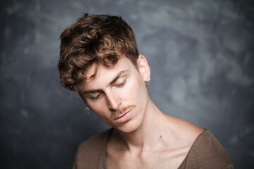 Selective focus portrait of a young blond man with blue eyes and mustache over a handpainted background