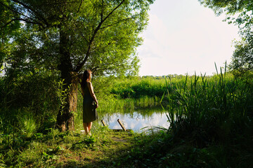Girl on the river on the sunny summer day in Russia.