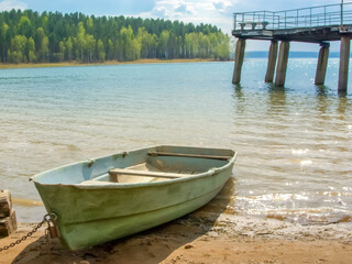 Obraz premium old wooden boat on the beach by the river on a sunny summer day