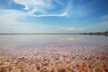 red saline lake under blue cloudy sky, summer natural background