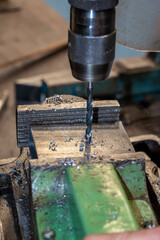 Work in the workshop and drill a hole with the drill in a piece of metal