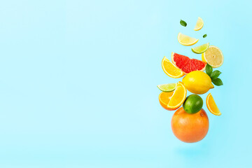 Mix of citrus fruits such as grapefruit, orange, lemon, lime in the middle on a blue background, soar in the air with copy space