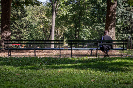 senior woman sitting on bench looking at park
