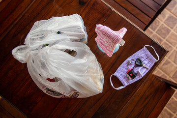 Compras em sacolas plásticas para serem desinfetadas antes de guardar. Máscara e álcool sobre a...