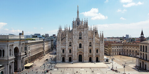 Naklejka premium Italy, Milan July 2020 - Drone aerial view of Duomo Cathedral after finish of lockdown due COVID-19 Coronavirus outbreak, people outside with mask and tourist in downtown and Vittorio Emanuele Gallery