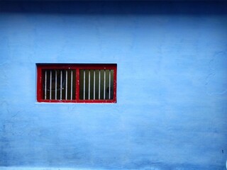 Plain blue wall with red window in india