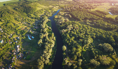 Aerial view on river near the village and forest