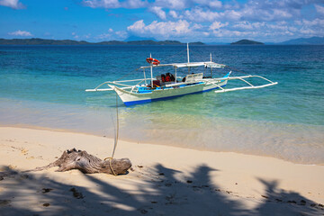 Empty wooden boat and white beach on sunny day. Tropical island paradise photo. Philippine island hopping tour. Exotic place for summer vacation. South Asia travel. Tourist resort relaxing view