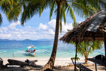 Coco palm tree and white beach on sunny day. Tropical island paradise photo. Rustic hut and traditional wooden boat. Exotic place for summer vacation. South Asia travel. Tourist resort relaxing view