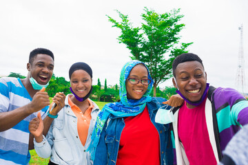 young black friends standing in a park and taking a selfie from the camera