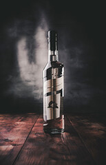 Alcohol bottle on dark background and wooden table.