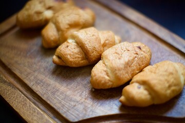 Close up view of homemade croissants. A few pieces of croissants on the serving board. Blurry background.