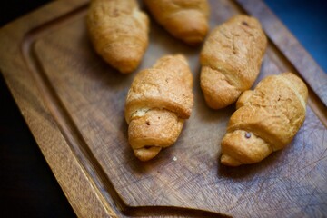 Close up view of homemade croissants. A few pieces of croissants on the serving board. Blurry background.