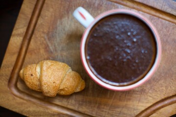 Aerial view of croissant and glass of black coffee. Blurry and black background. 
