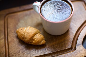 Aerial view of croissant and glass of black coffee. Blurry and black background. 
