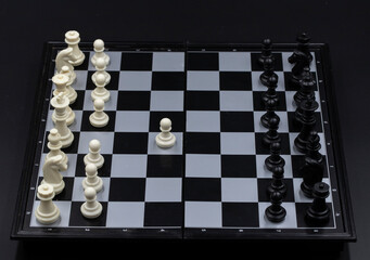 Chess game begin on chessboard. Checked board with figure on black background. Chess figurine...