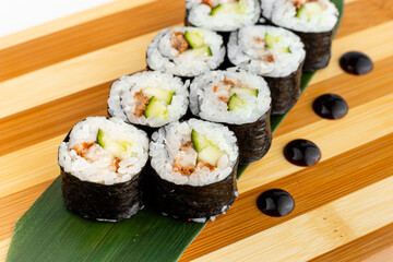 Maki Sushi Rolls set on wooden bamboo board. Japanese traditional Cuisine. White background.