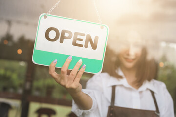 Woman hand open sign board on the door cafe or restaurant hang on door at entrance.