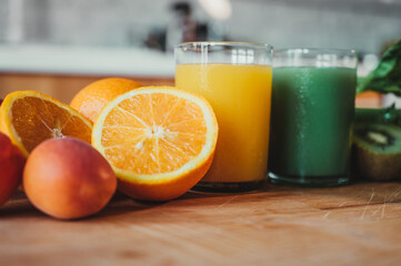 Orange juice with fresh oranges in the foreground and green juice in the background