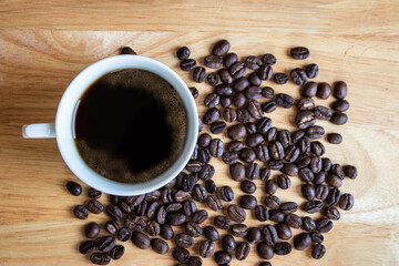 Black coffee placed on a wooden table with coffee beans.