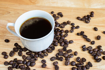 Black coffee placed on a wooden table with coffee beans.